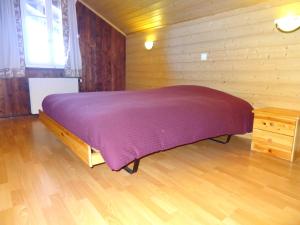 Un dormitorio con una cama con una manta morada. en Helvetia, en Troistorrents
