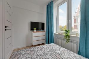 a bedroom with a bed and a tv and a window at Ideal Apartments Arkady in Gdańsk