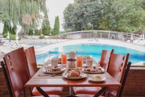 金沙的住宿－GRIFID Arabella Hotel - Ultra All inclusive & Aquapark，一张桌子,上面有盘子,放在游泳池边