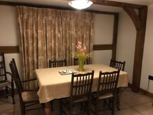 a dining room table with a vase of flowers on it at Cosy Cottage in the Countryside in Stafford