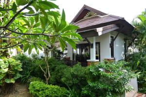 ein kleines weißes Haus mit Bäumen und Pflanzen in der Unterkunft Phangan Bayshore Resort Koh Phangan in Haad Rin