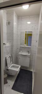 a white bathroom with a toilet and a sink at Apartment 906 in Prishtina in Pristina