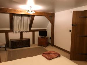 a bedroom with a bed with a ceiling fan and a television at Cosy Cottage in the Countryside in Stafford