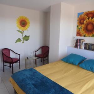 ein Schlafzimmer mit einem Bett, zwei Stühlen und einem Gemälde in der Unterkunft L'oustal des Fontanilles in Castelnaudary