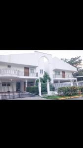ein großes weißes Haus mit einem Zaun davor in der Unterkunft Casa Duplex Privada con Piscina with Ride from Airport in Panama-Stadt