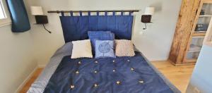 Una cama con sábanas azules y almohadas. en L'HIVERNET, grand Triplex neuf au cœur d'Embrun accès facile en Embrun