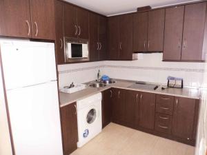 a kitchen with wooden cabinets and a washer and dryer at Isladescanso in Isla Cristina
