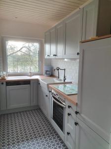 a kitchen with white cabinets and a sink and a window at Ferienhaus blauer See mit optionalem Hot-Tub in Bockhorn