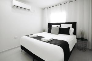 une chambre blanche avec un grand lit avec des oreillers noirs et blancs dans l'établissement YalaRent Villa Enorma with Private Pool, à Eilat