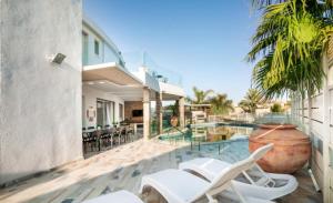 une terrasse avec des chaises blanches et une piscine dans l'établissement YalaRent Villa Enorma with Private Pool, à Eilat