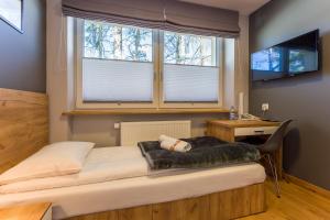 a bedroom with a bed and a desk and two windows at Hotel***Gorce in Nowy Targ