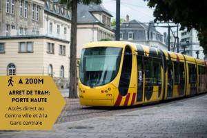 a yellow tram on a city street with a sign at Le convivial, appartement Centre ville Mulhouse in Mulhouse