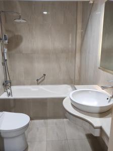 a bathroom with a toilet and a tub and a sink at Hotel Indah Palace Yogyakarta in Yogyakarta