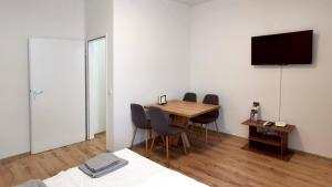 Zimmer mit einem Tisch und Stühlen sowie einem TV in der Unterkunft Bacher Apartment in Wien