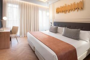 1 dormitorio con 1 cama blanca grande y escritorio en Catalonia Goya en Madrid
