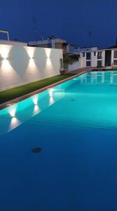 a large swimming pool with blue water at night at PURA B&b in Noicattaro