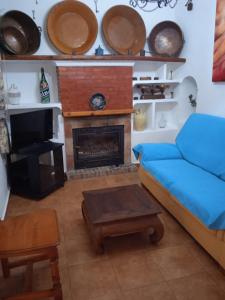Casa Rural El Castillo في مالقة: غرفة معيشة مع أريكة ومدفأة