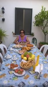 Uma mulher sentada à mesa com comida. em B&B ERMINIA em Laino Borgo