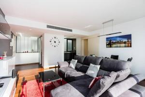 Modern Luxury Apartment Fira Bcn في لوسبيتاليت دي يوبريغات: غرفة معيشة مع أريكة وساعة على الحائط
