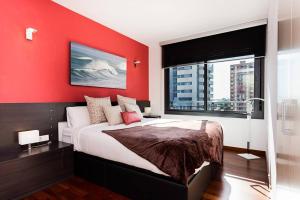 Modern Luxury Apartment Fira Bcn في لوسبيتاليت دي يوبريغات: غرفة نوم حمراء بها سرير كبير ونافذة