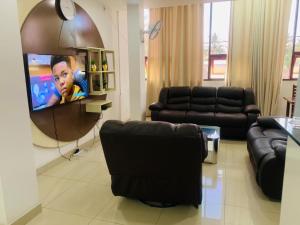 RESIDENCIAL AFRICA,LDA-NAMPULA في نامبولا: غرفة معيشة مع أثاث أسود وتلفزيون بشاشة مسطحة