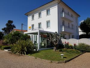 un edificio blanco con un jardín delante de él en The Originals Access, Hôtel Corinna, Royan, en Royan