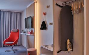 ein Hotelzimmer mit einem roten Stuhl und einem Schlafzimmer in der Unterkunft Holiday Inn Express Berlin City Centre, an IHG Hotel in Berlin