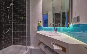 ein Badezimmer mit einem Waschbecken, einer Badewanne und einem Spiegel in der Unterkunft Holiday Inn Express Dortmund, an IHG Hotel in Dortmund