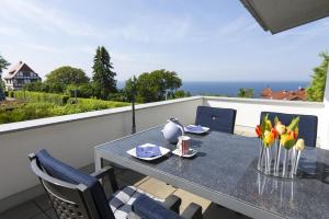 a table and chairs on a balcony with a view of the ocean at schöner Meerblick von der Dachterrasse Haus Ostseeblick 1 FeWo Meehrblick in Lohme