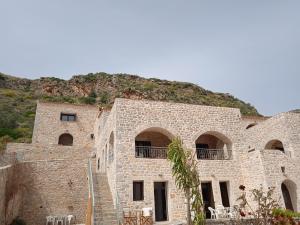 a stone building with arched windows and a mountain at Mani Blue Studios in Oítilon