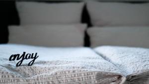 a white bed with the word enjoy written on it at schöne 2-Raum-Ferienwohnung mit Terrasse - Haus Ostseeblick 1 FeWo Steuerbord in Lohme