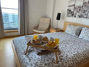 a breakfast tray on a bed with orange juice and bread at Suites Panoramic - River View in Lisbon
