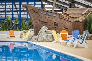 a beach with a pool, chairs, chairs and a boat at Marine Holiday Park in Rhyl
