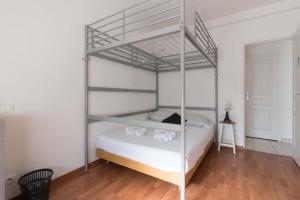 - une chambre avec des lits superposés en métal et des draps blancs dans l'établissement LES CELTES - Appartement pour 6, à Saint-Nazaire