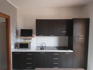a kitchen with black cabinets and a sink and a microwave at Bilocale RESIDENCE MARASUSA in Parghelia