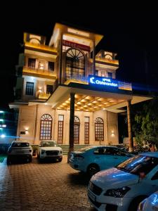 马图拉Hotel Abhinandan的停车场里停着汽车的建筑物