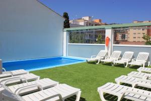 a patio with white chairs and a swimming pool at Hotel Armonía in Lloret de Mar