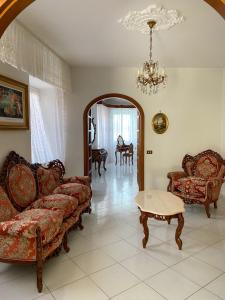 uma sala de estar com sofás, uma mesa e um lustre em A~Mare Casa Vacanze em Fezzano