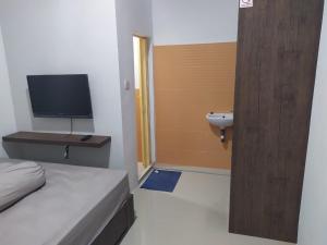 een slaapkamer met een bed, een wastafel en een televisie bij Rooms at Josapa Guest House in Batam Center