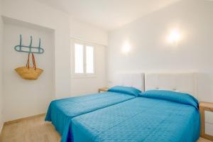 um quarto com uma cama com lençóis azuis e uma janela em Dols mar apartments em Camp de Mar
