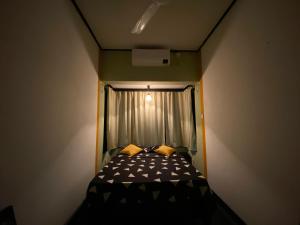 un piccolo letto in una piccola stanza con finestra di Clover Grange Home Stay a Matale