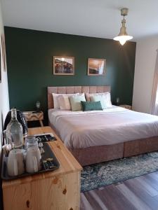1 dormitorio con 1 cama con pared verde en The Sleepy Leprechaun, en Doolin