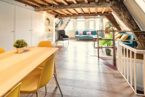 - un salon avec une table en bois et des chaises jaunes dans l'établissement The Charming Hendrik Square Apartments, à Anvers