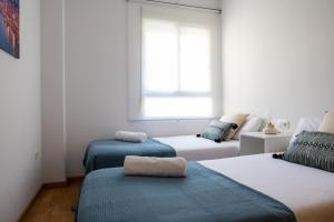 een witte kamer met 3 bedden en een raam bij Medinaceli airco, wifi and free parking in Valencia