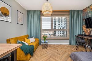 a living room with a yellow couch and a window at Bastion Wałowa by Q4Apartments in Gdańsk