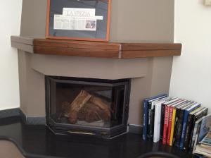 a fireplace with logs and books on a table at Hotel Il Saraceno in Volastra