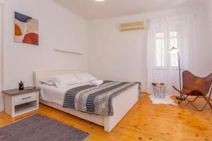 a white bedroom with a bed and a chair at Old Market Residence in Šibenik