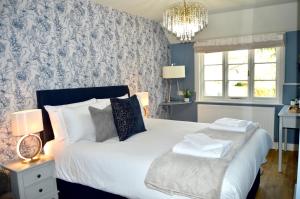 a bedroom with a large white bed and a chandelier at The Nest Hotel & Restaurant in Petersfield