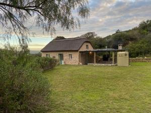 ein Steinhaus auf einem Feld mit einem Hof in der Unterkunft Paddahoek Cottage in Vermaaklikheid