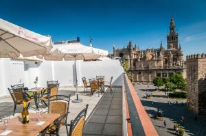 an outdoor patio with tables and chairs and a cathedral at Suites Murillo Alcázar in Seville